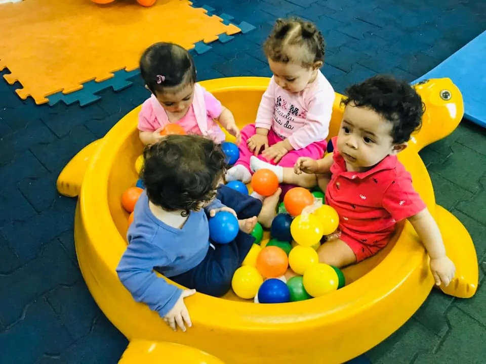Bebês do berçário brincando na piscina de bolinhas